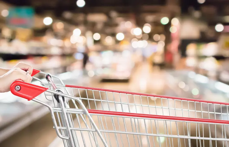 Wózek sklepowy na tle alejki w supermarkecie