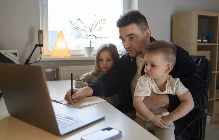 Mężczyzna podczas pracy na komputerze zajmuje się dwójką dzieci